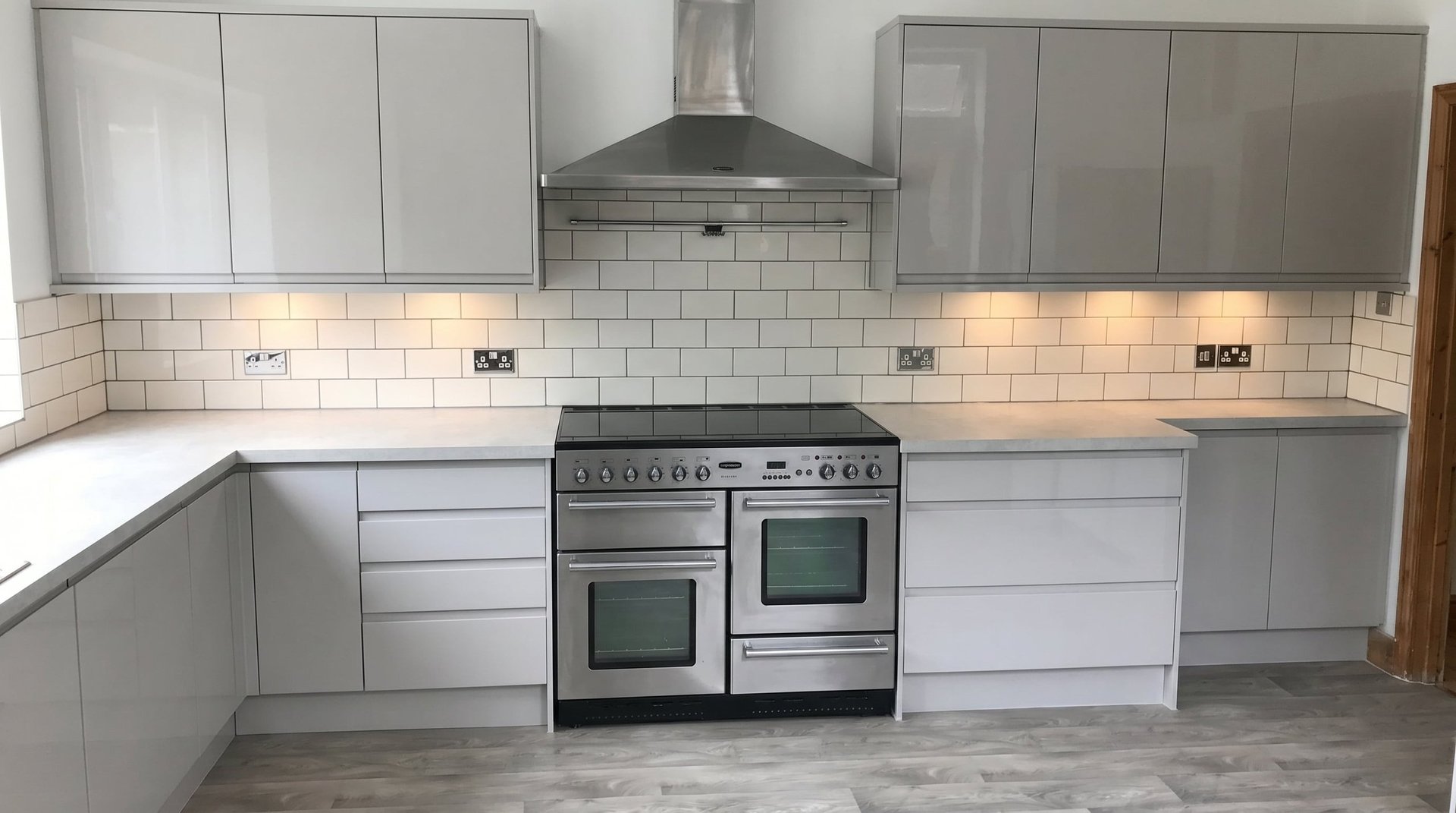 Modern gray and white kitchen with subway tile backsplash, stainless steel dual oven range, and white countertops