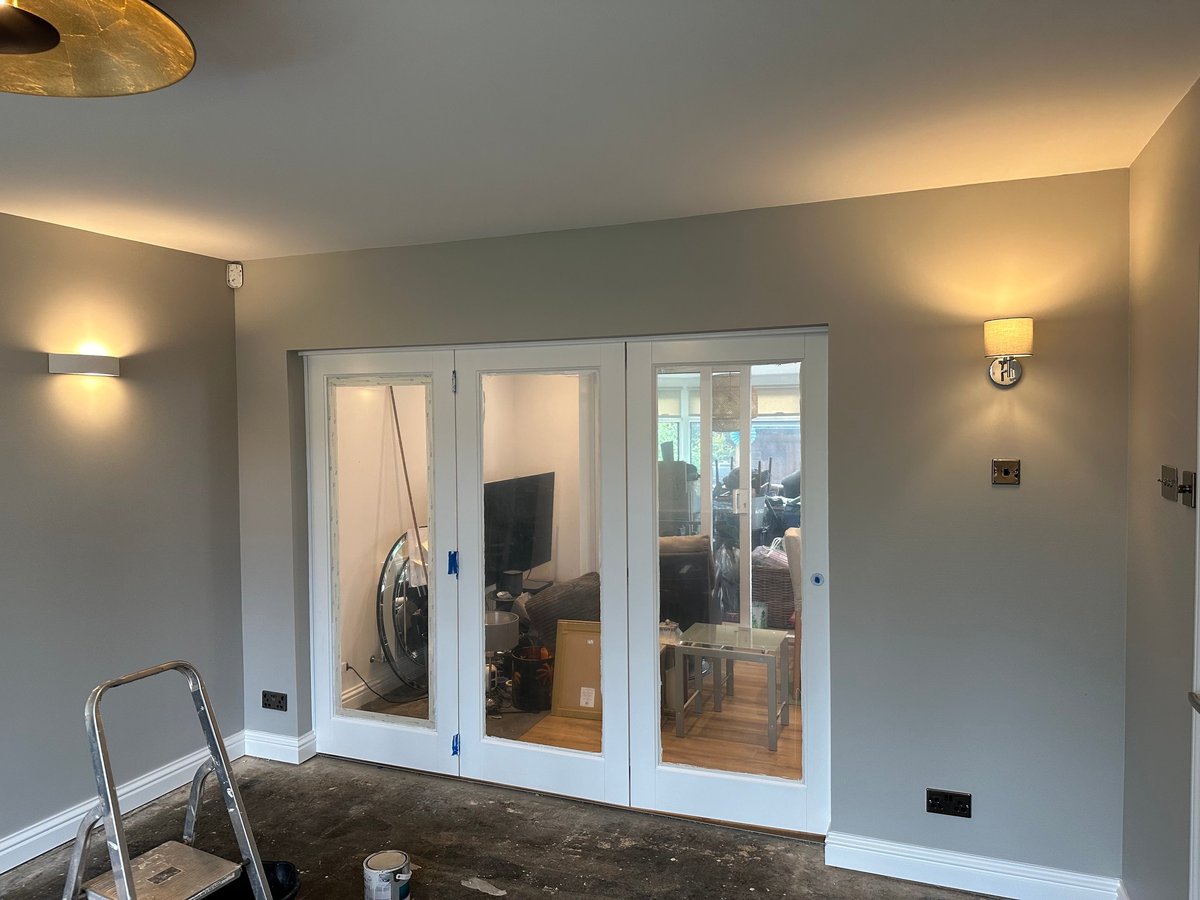 Modern interior room with white triple French doors, soft wall sconces, and cream-colored walls