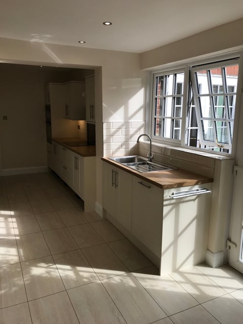 Modern kitchen with cream cabinets, stainless steel sink, and large window overlooking residential street